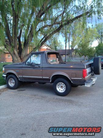 1992 Ford Bronco parked on asphalt, side view. Spare tire mounted on rear carrier