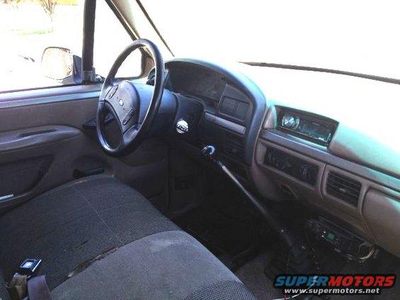Interior shot of a truck's dashboard, steering wheel, and passenger seat