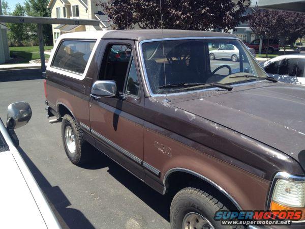 Brown 1992 Ford Bronco with white top, parked outdoors. Visible damage on hood