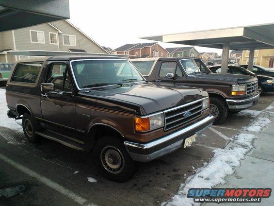 Brown Ford Bronco parked under a carport, with another truck behind it