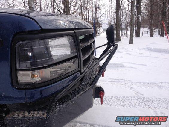 Blue truck front end with aftermarket bumper and winch in snow