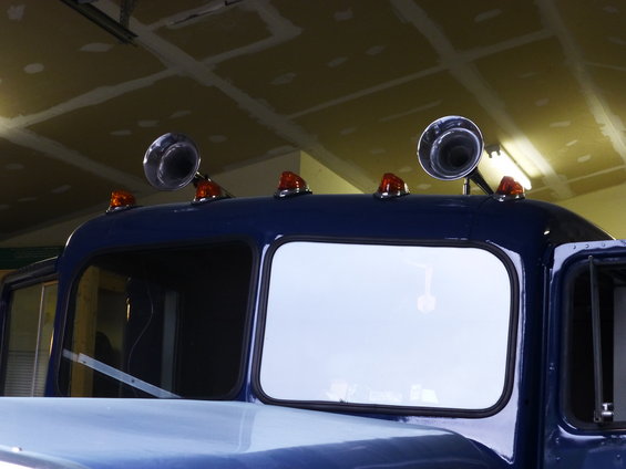 Blue truck cab roof with two chrome air horns and four amber marker lights