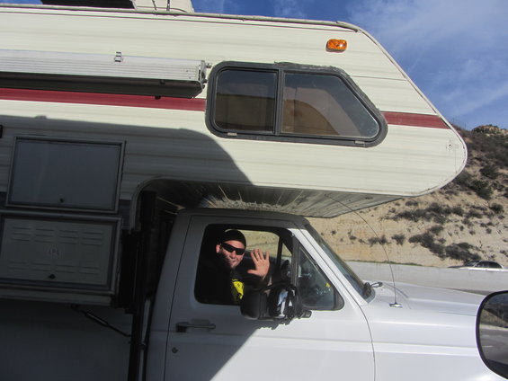 guy in driver's seat of white camper van, waving