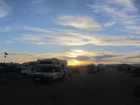 Trucks and RVs parked in a desert area at sunset