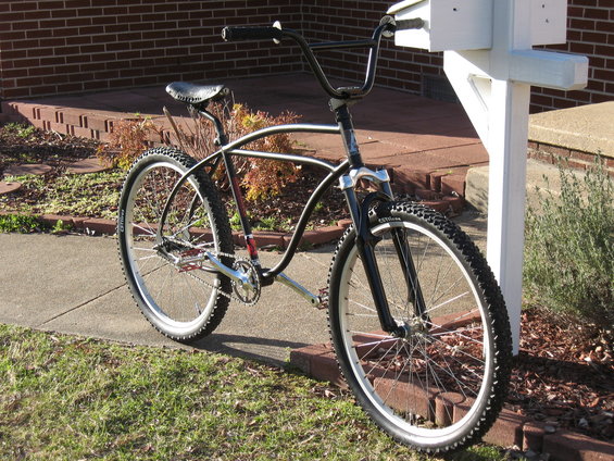 Black cruiser bicycle with wide handlebars parked next to a white mailbox