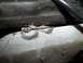 1990 Ford Bronco - Close-up of a rusted metal bracket and wire, likely from a vehicle's undercarriage or engine bay.