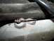 1990 Ford Bronco - Detail of a corroded metal bracket and pipe, likely from a vehicle's undercarriage.