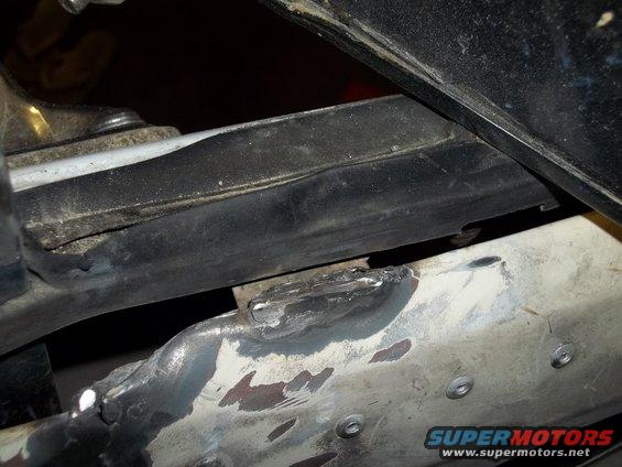 Close-up of welded metal on a vehicle frame, with some black rubber trim above it