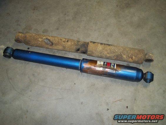 old rusty shock absorber next to a new blue one with a label