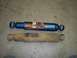 1990 Ford Bronco - A new blue shock absorber is compared to a heavily rusted old one on a garage floor.
