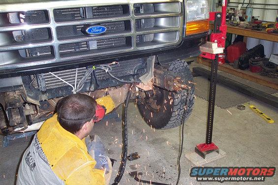 Ford truck front end being welded, with a Hi-Lift jack nearby