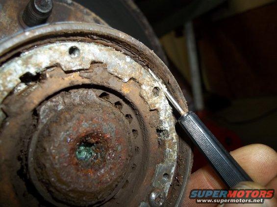 Rusty brake drum assembly being worked on with a pick tool