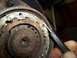 1990 Ford Bronco - Close-up of a rusty brake drum assembly, with a pick tool being used to clean or inspect a part of the components.