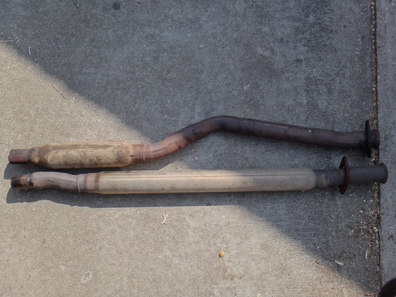 Two exhaust mufflers and pipes laid on concrete