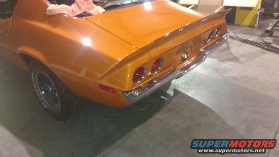 Orange 1973 Chevrolet Camaro with a rear spoiler and chrome bumper, viewed from the rear