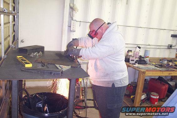 Person in a workshop welding metal on a table, sparks flying