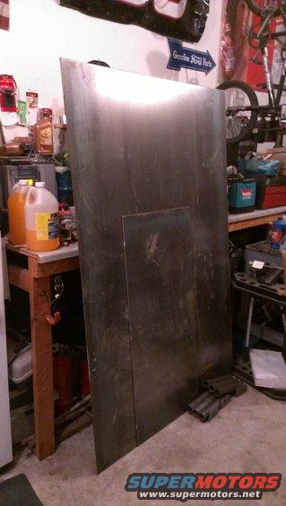 Large sheet of metal leaning in a workshop, with a smaller piece on top. "Genuine Ford Parts" sign on wall