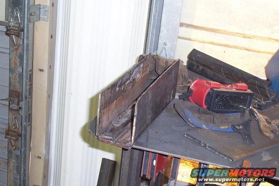 Metal bracket on workbench with welding helmet and tools