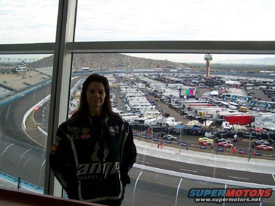 Woman in racing jacket overlooking a speedway with many RVs and cars in the parking area