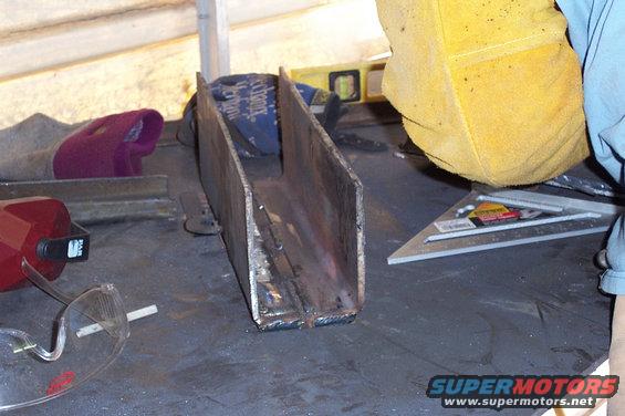 metal channel welded together on a workbench with safety glasses and a welding mask nearby