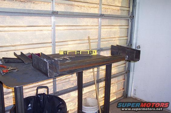 Metal pieces welded together on a workbench with a level and tools nearby