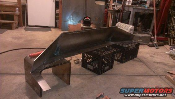 Metal bumper part on milk crates, with welding equipment nearby