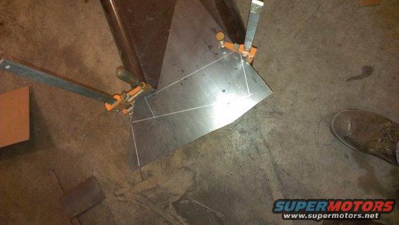 Metal sheet clamped for fabrication, showing cut lines