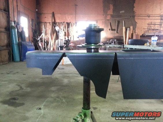 Custom bumper sections on a stand in a workshop, with tools and tanks in background