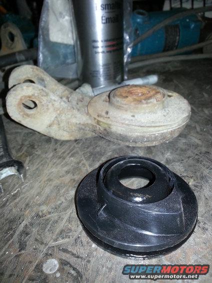 rusty metal suspension component and a black rubber part on a workbench