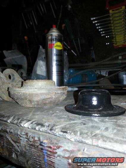 Black rubber car part next to a rusty metal car part on a workbench