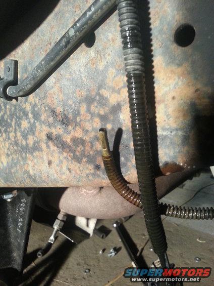 Close-up of rusty frame with black and ribbed hoses attached