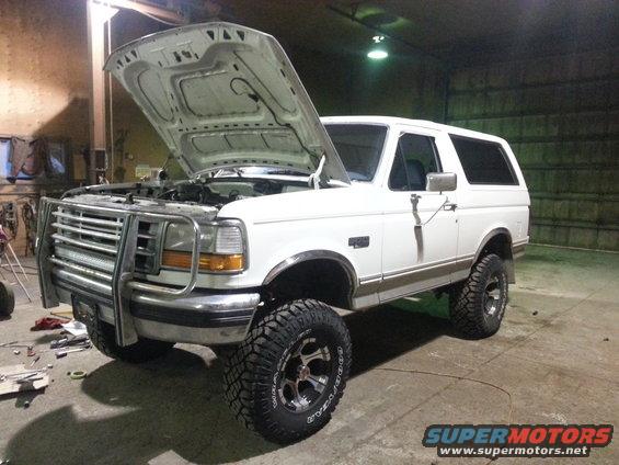 White Ford Bronco with hood up, lifted suspension, and brush guard