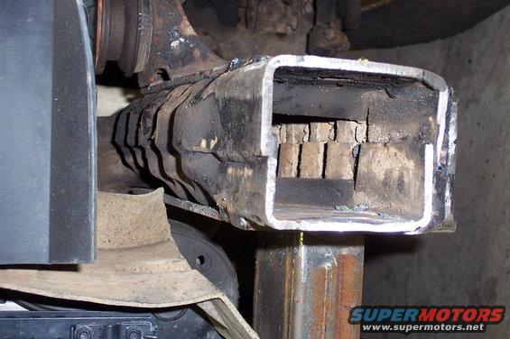close-up of a welded metal pipe with internal baffles, part of a vehicle's exhaust system