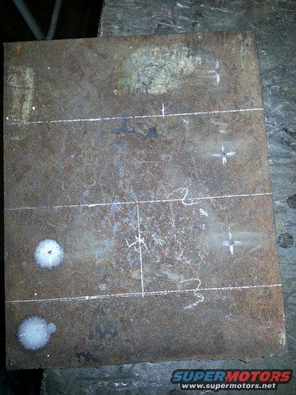 Rusty metal plate with horizontal and vertical scribe lines, plus several drill marks