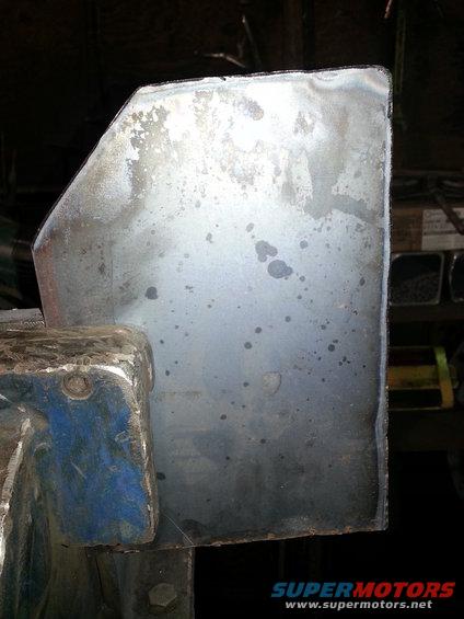 Metal panel with stains, held by a blue vise