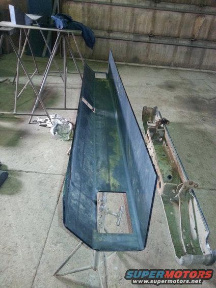 Two disassembled car bumper sections, one dark blue, one metallic, on a concrete floor