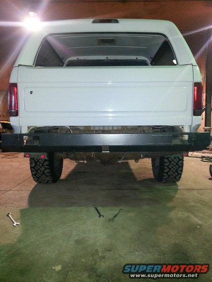 White SUV rear view, missing bumper, aftermarket tow hitch, off-road tires