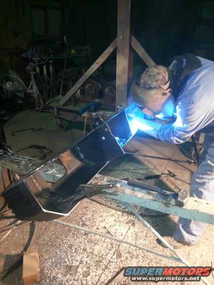Welder working on a black metal part in a workshop