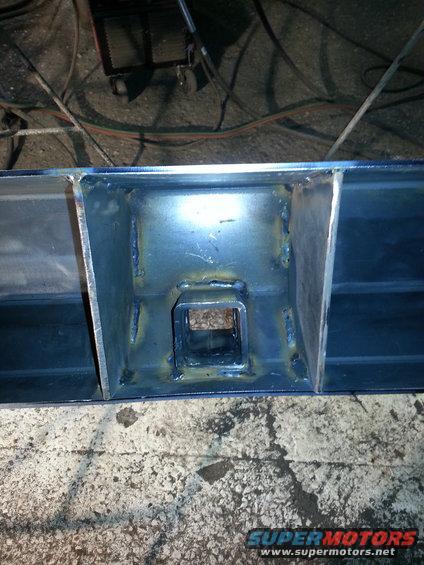 Welded steel frame with square receiver hitch opening, blue metal, rough welds