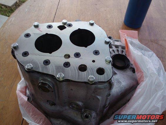 Close-up of a metal automotive transmission housing with bolts and two circular openings