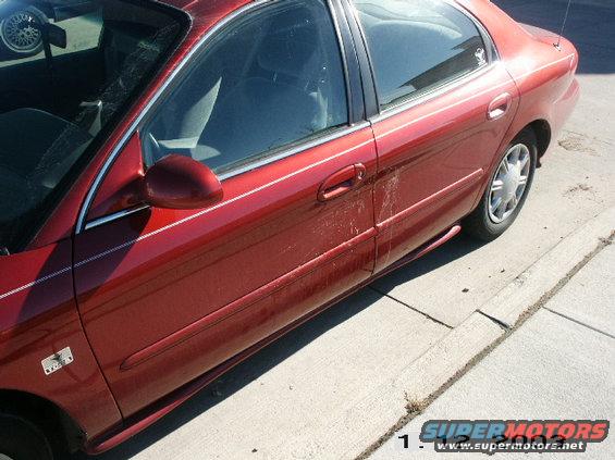side view of red sedan with white pinstripes and some dirt on the door