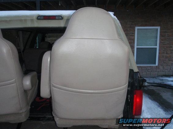 Tan leather captain's chairs in a vehicle interior, with snow visible outside