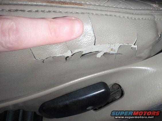 Tan leather car seat with cracked and peeling upholstery, close-up on damage