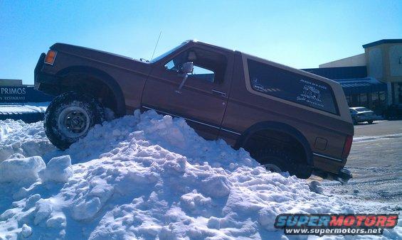 Brown 1987 Ford Bronco climbing a snow pile