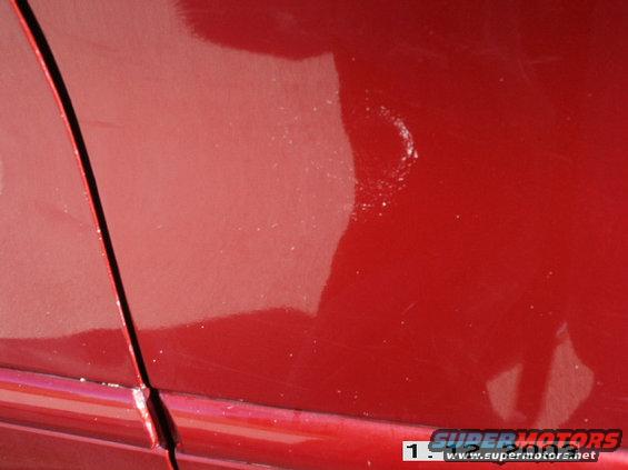 Red car door seam with minor paint imperfections