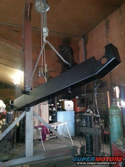 black metal beam hanging from chain hoist in workshop