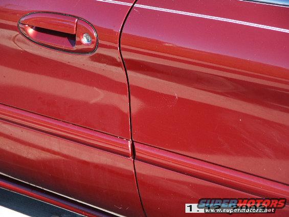 Red car door and fender with chrome trim, showing a scratch and a keyhole
