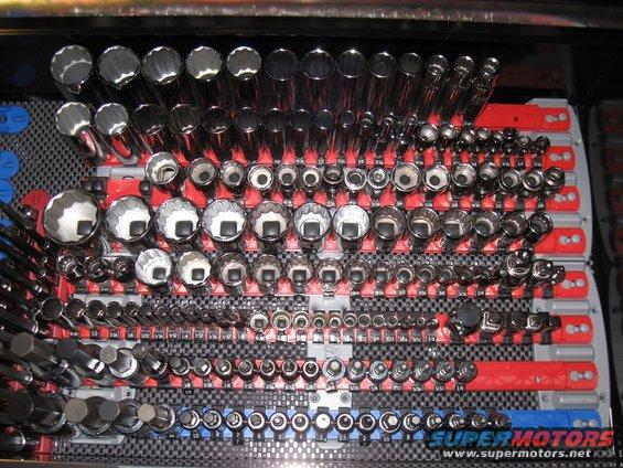 Tool organizer filled with various sockets and wrenches, some labeled with sizes