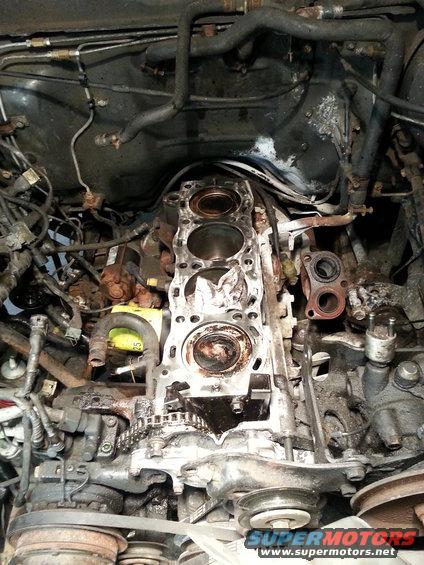 Engine block with cylinder head removed, showing pistons and timing chain