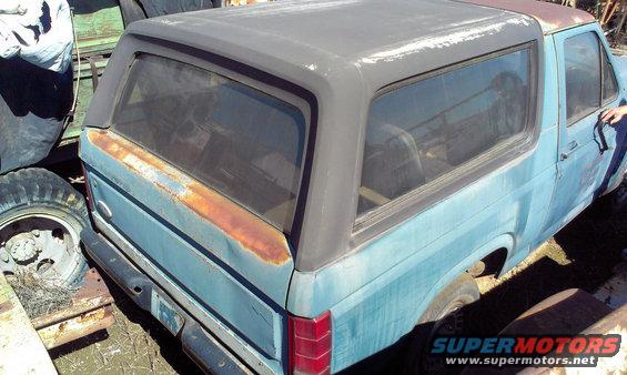 Blue Ford Bronco with rust on the rear quarter panel and a black removable top